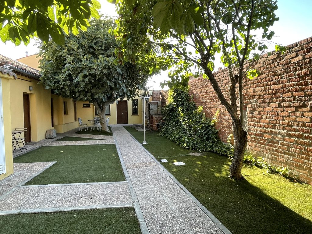 Patio interior con arboles mesas y sillas de Apartamentos Ajates